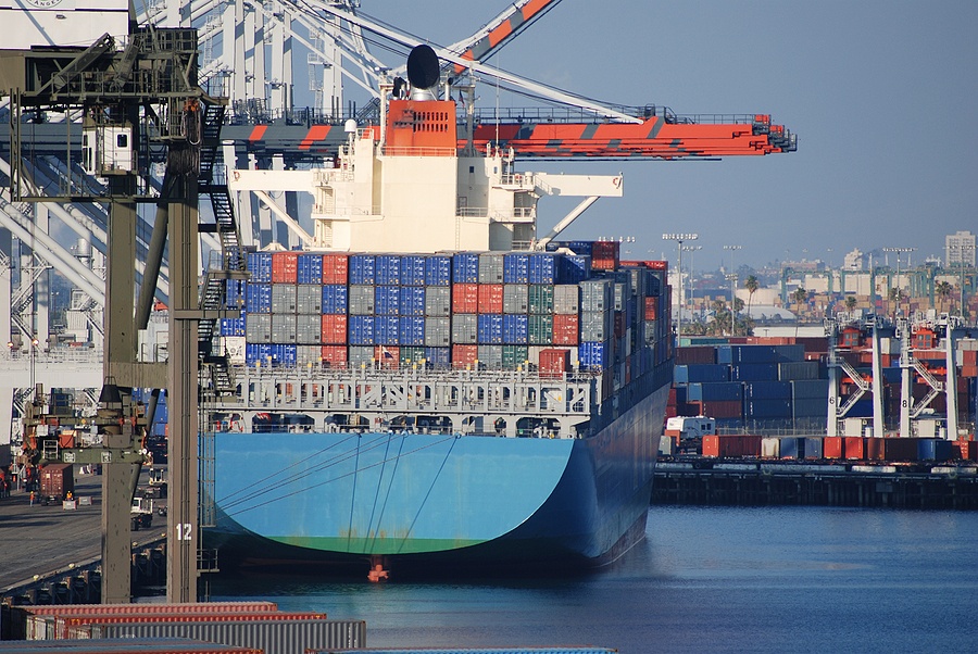 A ship being loaded with cargo containers by cranes.