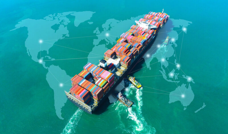 Aerial view of a cargo ship in an open seaport, illustrating international logistics and trade.