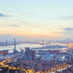 Aerial view of the Port of Guangzhou at sunset, showing shipping terminals and bridge connections. The Port of Nansha, part of the Guangzhou complex, is a key hub for exports from South China to the U.S.