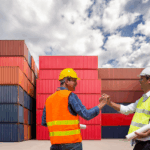 Two logistics professionals shaking hands in front of shipping containers, symbolizing strategic partnerships during the 2026 contracting season