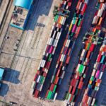 Aerial view of a shipping port with colorful containers representing global trade compliance and 2026 tariff update