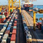 Multimodal freight operations supporting Shipping from China to Europe, showing rail cargo, container trucks, and ocean vessel at a European port terminal.