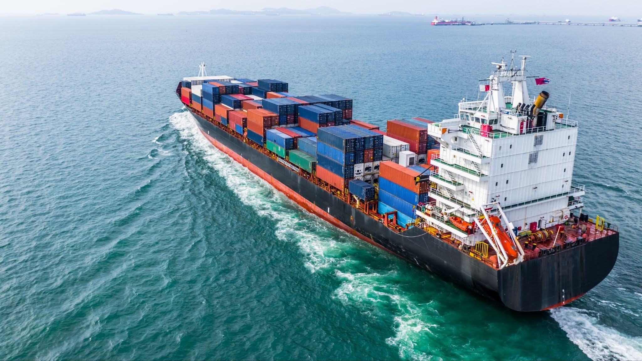 Cargo container ship transporting goods internationally, illustrating strategies to reduce import costs and MPF fees