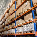 Large industrial warehouse with organized shelving units filled with labeled boxes and pallets, illustrating storage and inventory management typical of a customs bonded warehouse in India.
