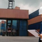 Logistics professional reviewing shipping documents at a container terminal as tariff deadlines impact global supply chain planning.