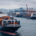 Container ships moving through a busy port with cranes and stacked containers in the background