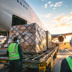Air cargo ground handlers loading palletized freight onto an aircraft, illustrating air freight terminal handling charges and airport cargo operations.